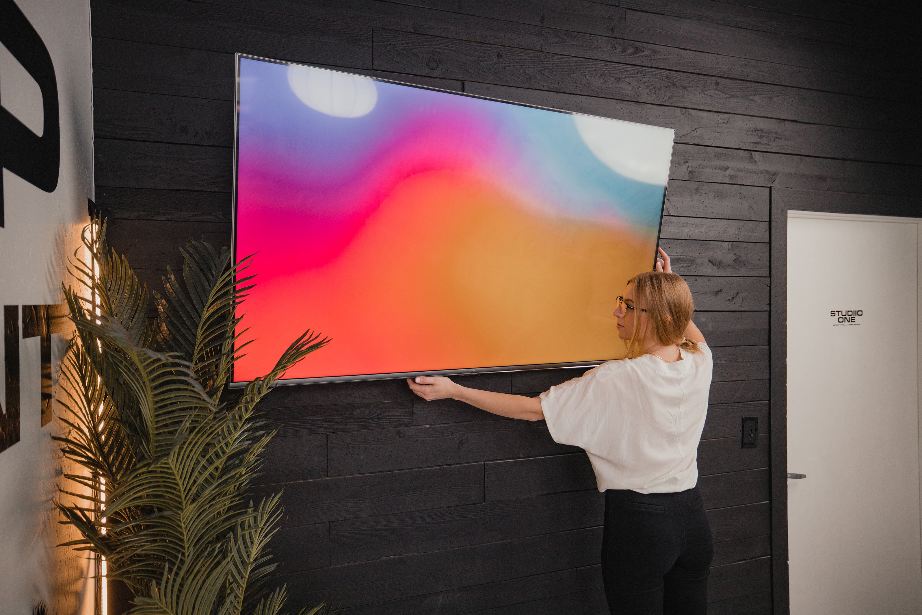 woman fixing a mounted tv 