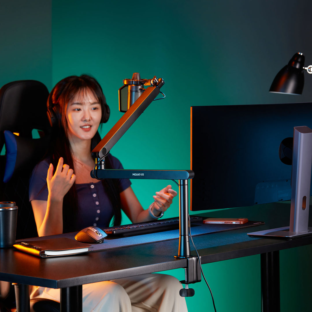 a woman sitting at a desk with a computer and boom arm