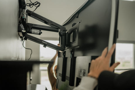 a person holding a tv up to mount it on the wal