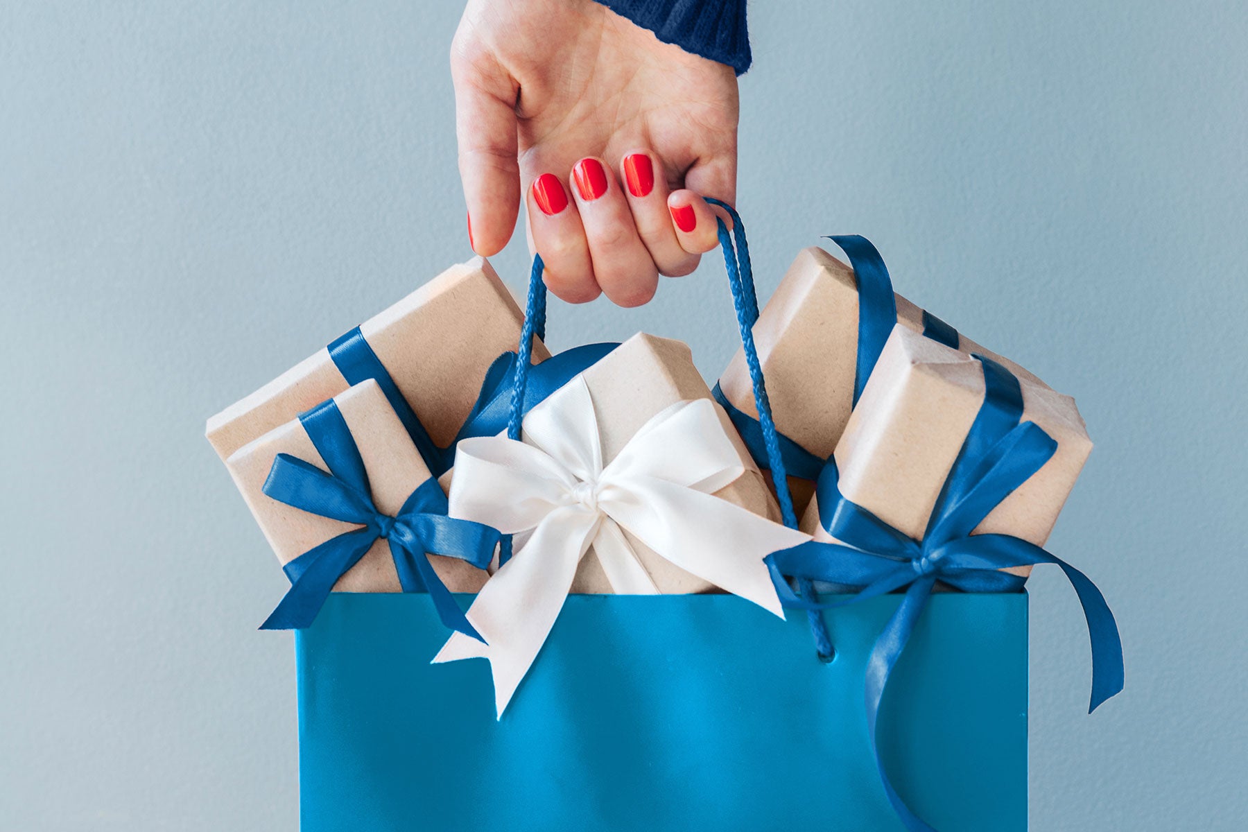 a woman's hand holding a blue gift bag