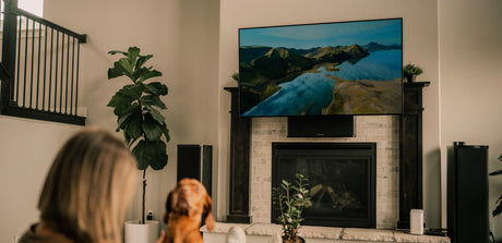 a woman sitting in front of a fireplace watching tv