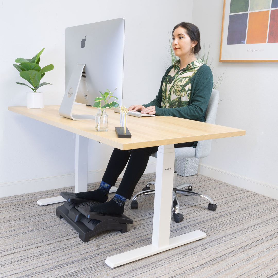 a woman sitting at a desk using a computer resting her feet